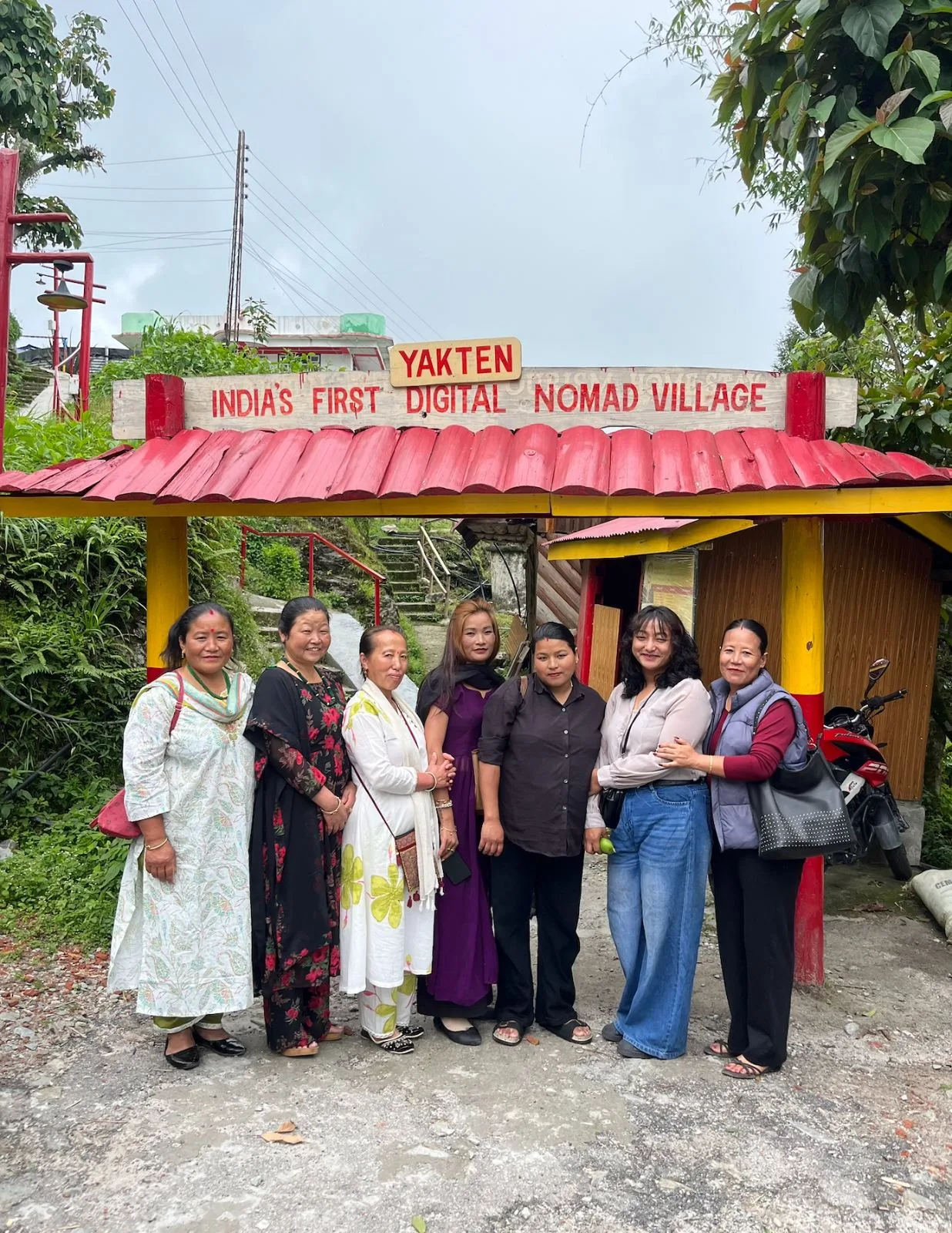 The didis of Yakten at the village gate, under the sign reading India's first digital nomad village