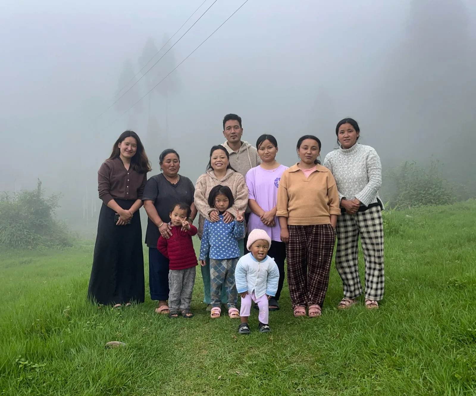Host families of Gumpadara standing together on the grass in morning mist