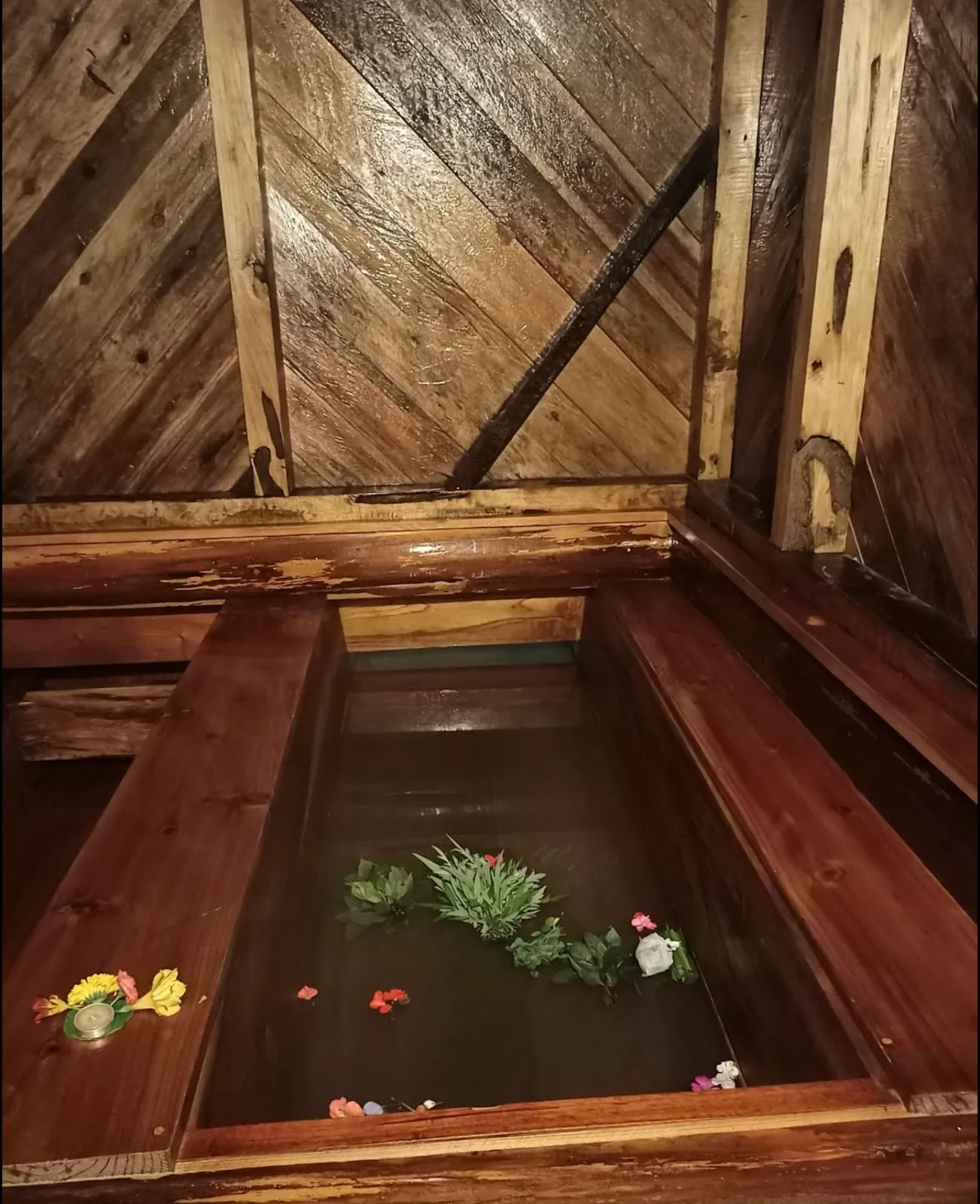 A wooden hot stone bath filled with water and flowers