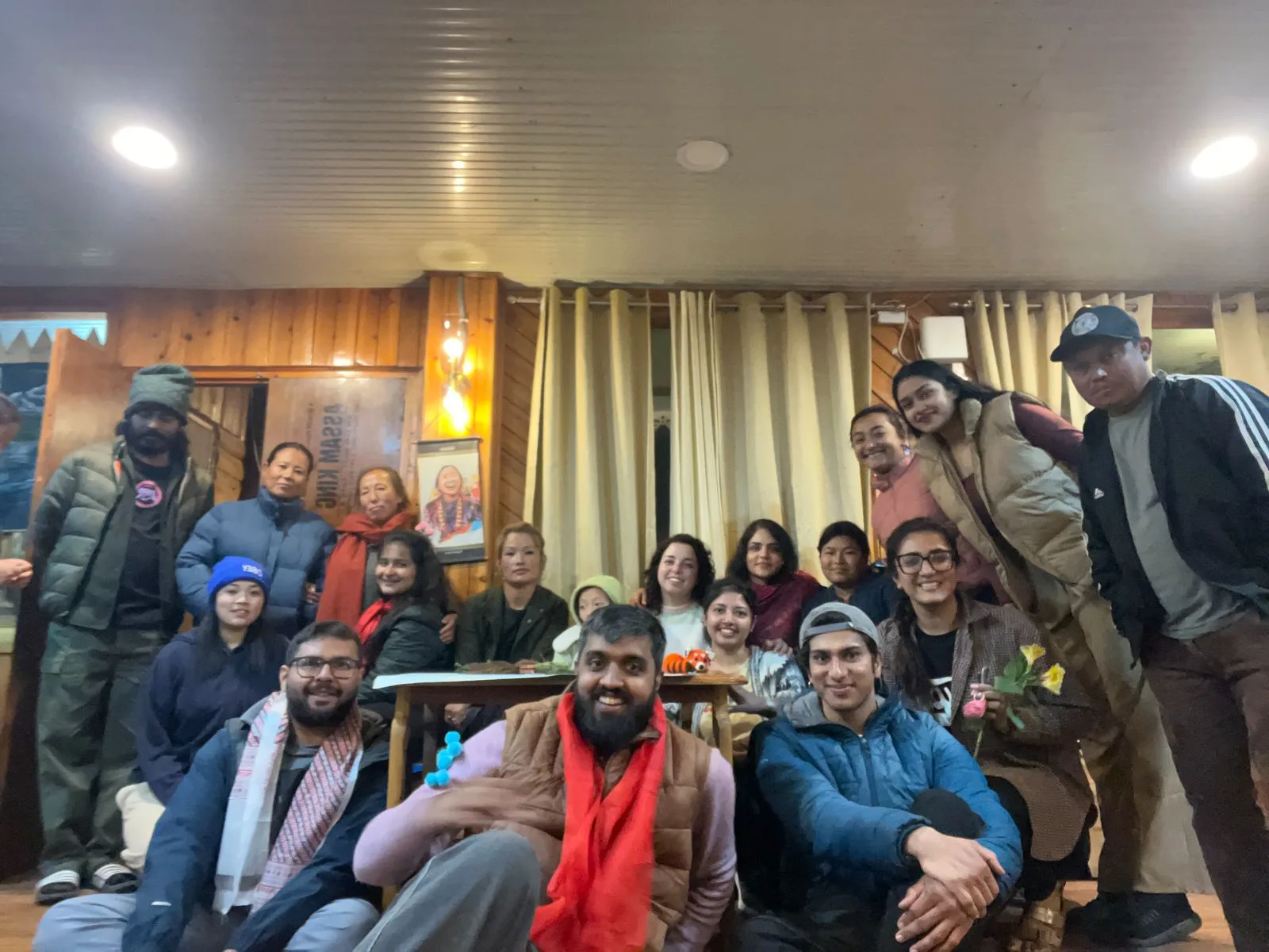 Guests and host families gathered together around a table in a homestay dining room in the evening